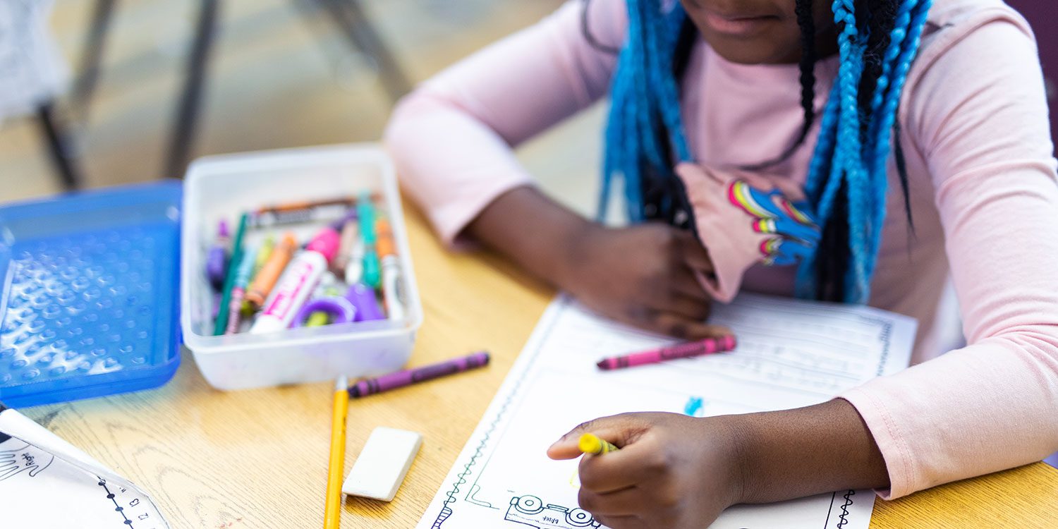 Student coloring at desk.